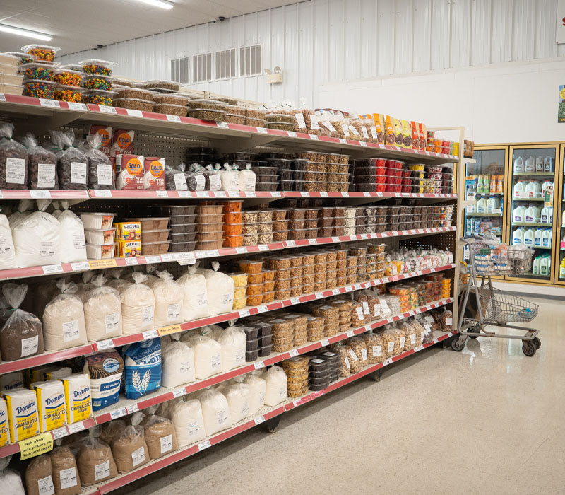 Grocery store shelves stocked with bulk baking ingredients and snacks.