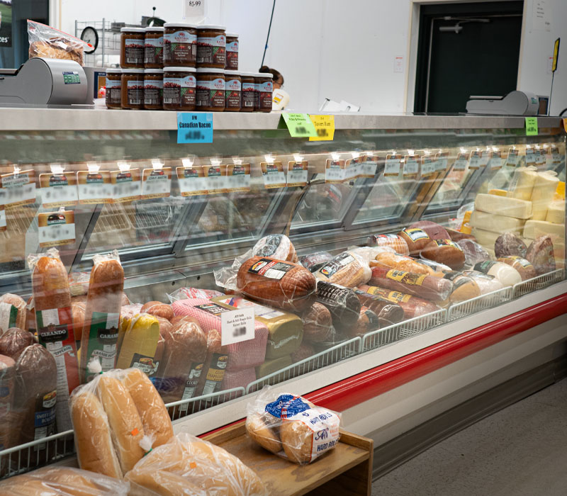 A deli service counter and refrigerated display case filled with deli meat and cheeses.