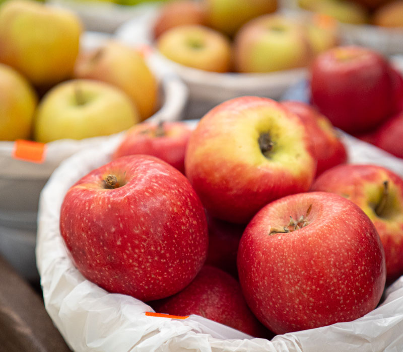 Baskets of fresh red and yellow apples displayed at a grocery store or market produce stand.